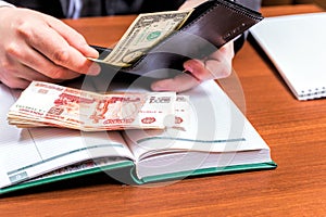 Businessman holding wallet with dollars and makes entries in the diary