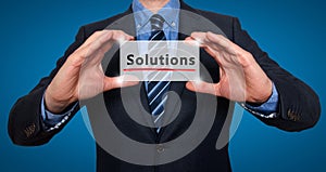 Businessman holding white card with Solutions sign, Blue - Stock