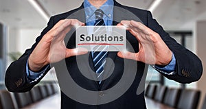 Businessman holding white card with Solutions sign, Office - Stock Photo