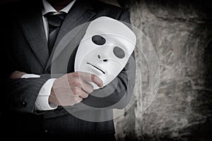 Businessman holding white mask in his hand dishonest cheating agreement.Faking and betray business partnership concept photo
