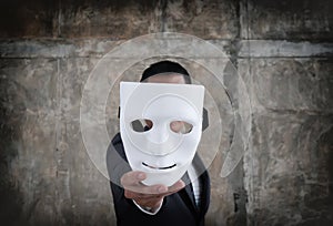 Businessman holding white mask in his hand dishonest cheating agreement.Faking and betray business partnership concept photo