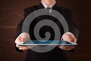 Businessman holding a white modern tablet with blurry apps