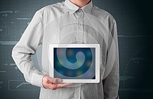 Businessman holding a white modern tablet with blurry apps