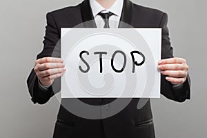 Businessman holding white paper board with stop sign