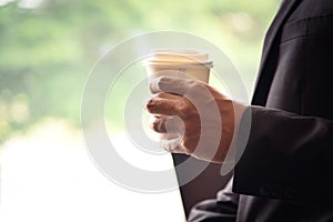 Businessman holding white paper coffee cup in hand