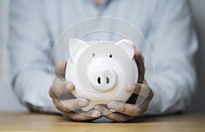 Businessman holding white piggy bank for deposit and money saving investment concept