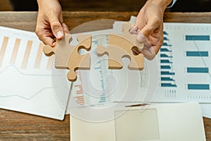 Businessman holding wood jigsaw in office. Business solutions, success, goals and teamwork concept