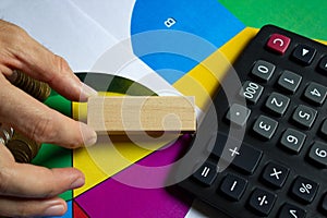 Businessman holding a wooden block in his hand next to a calculator and color charts. Planning,risk and project management