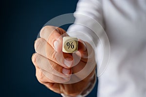 Businessman holding wooden dice with % sign