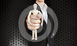 Businessman holding wooden figure, on black aluminum texture background