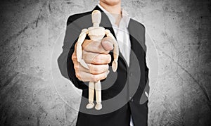 Businessman holding wooden figure, on concrete texture background