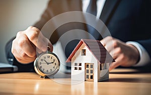 Businessman holding a wooden house and clock. Mortgage, real estate and loan concept. Tax payment. Construction investment.