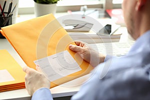 Businessman holding yellow package with mail in office