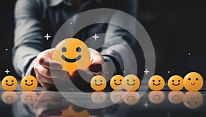 Businessman holding yellow smiley face emoticon. Positive feedback and customer satisfaction concept