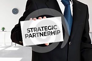 Businessman holds a card with the message strategic partnership photo
