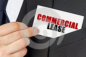 Businessman holds a card with the text - COMMERCIAL LEASE