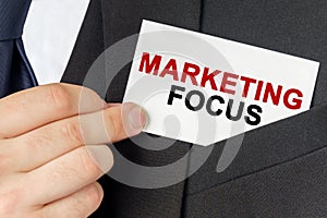 Businessman holds a card with the text - MARKETING FOCUS