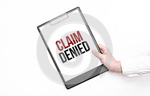 A businessman holds a folder with paper sheet with the text CLAIM DENIED . Business concept