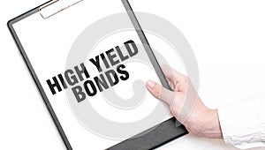 A businessman holds a folder with paper sheet with the text HIGH YELD BONDS. Business concept