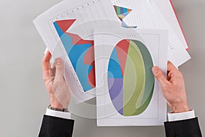 Businessman holds in hand documents with graphs and charts.