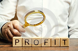 Businessman holds a magnifying glass over the word Profit. The concept of profitability and performance of business. Analysis of photo