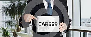 Businessman holds a signboard and points his finger to the word career. Business career