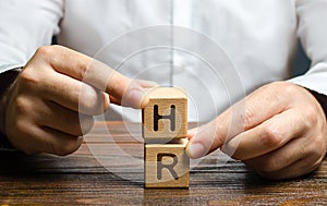 Businessman holds two blocks with letters HR. Recruiting new workers, headhunters Human resources. Attraction personnel