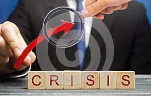 Businessman holds up arrow over blocks with the word Crisis. Increase instability of business and economy. Recession, stagnation, photo