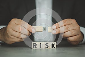Businessman holds usb flash drive in his hand and word text RISK wood block