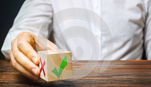 Businessman holds a wooden block with a green check mark. The concept of choice and making the right decision. Business management