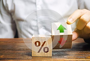 Businessman holds wooden blocks with percent and up or down arrow. Mortgage and loan rates. Interest rate, stocks, ranking.