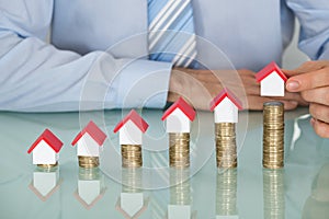 Businessman With House Model On Stacked Coins