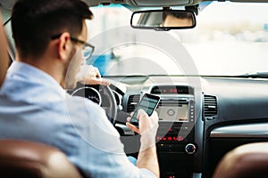 Businessman ignoring safety and texting onmobile phone while driving