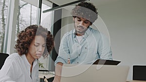 Businessman indian executive manager ceo talking to female African American coworker, using laptop. Diverse