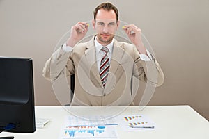 Businessman inserting earplug in ears