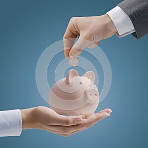 Businessman inserting money in a piggy bank