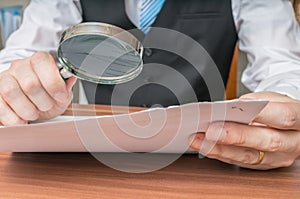 Businessman is inspecting contract with magnifying glass