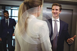 Businessman interacting with his female colleague near elevator