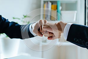 Businessman investor hand to fist bumping and joining hands together after complete business deal in meeting room