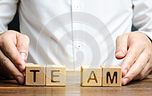 A businessman joins together two parts of the word Team. personnel management, the organization and creation of working groups