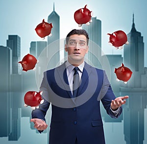 Businessman juggling with piggybanks in business concept