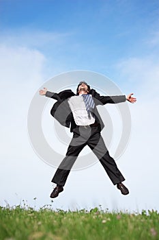 Businessman jumping on the meadow