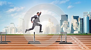 The businessman jumping over barriers in business concept