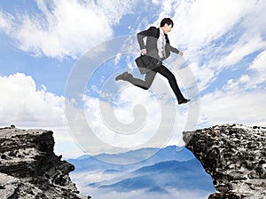 Businessman jumping over danger precipice photo