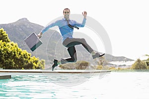 Businessman jumping over swimming pool