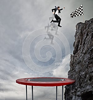 Businessman jumping on a trampoline to reach the flag. Achievement business goal and Difficult career concept