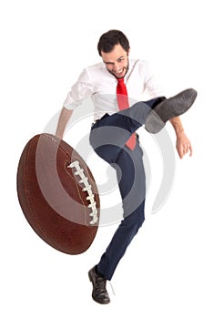 Businessman kicking an American football ball