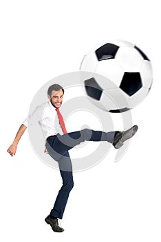 Businessman kicking a football isolated in white