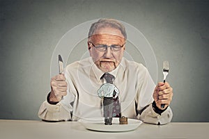 Businessman with knife and fork looking at his employee on a plate