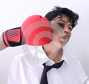 Businessman knocked out by getting punched in his face with red boxing gloves on white background